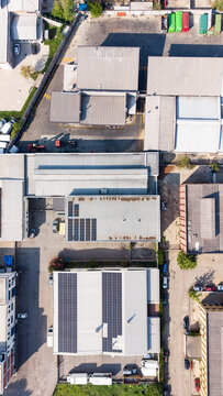 Aerial view of an industrial zone featuring warehouses with solar panel installations, parking lots, and access roads in Milan, Lombardy, Italy.
