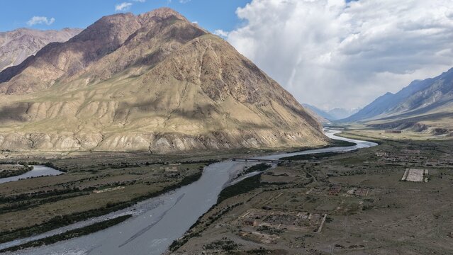 Aerial view of the Engilchek Glacier valley with a winding river, rugged mountain slopes, and sparse vegetation in Ak-Su, Issyk-Kul Region, Kyrgyzstan.