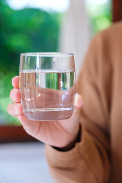 Vertical closeup image of a woman holding a glass of drinking water