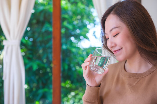 Portrait image of a woman holding and drinking water at home