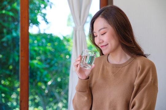 Portrait image of a woman holding and drinking water at home