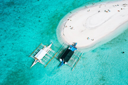 Aerial view of Sumilon Island sandbar with traditional outrigger boats anchored in the turquoise waters of Oslob, Cebu, Philippines.