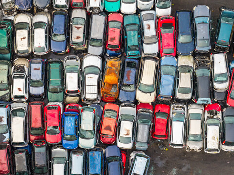 Aerial view of an end of life vehicle recycling facility with rows of salvaged cars in various colors and states of disrepair parked on a paved lot in Gdansk, Pomeranian Voivodeshi, Poland.