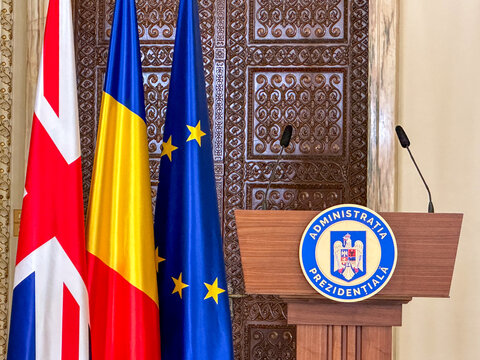 Bucharest, Romania - October 15 2023: Official press podium of Romanian Presidential Administration with microphones and national flags of Romania, UK and EU.