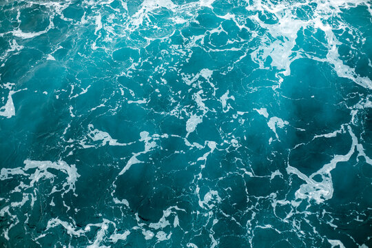 Ocean surface with gentle ripples and sparkling sunlight reflections, creating a calm, serene natural background with beautiful water texture.