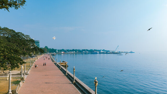 Aerial view of the Rizal Boulevard promenade with its iconic red brick path, lush trees, and street lamps along the coastline in Dumaguete City, Negros Island Region, Philippines.