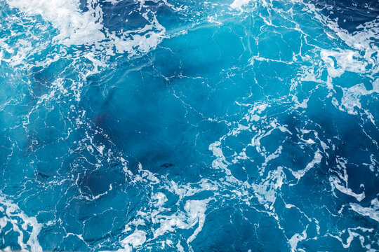 Ocean surface with gentle ripples and sparkling sunlight reflections, creating a calm, serene natural background with beautiful water texture.