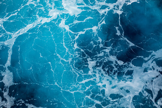 Blue ocean surface with gentle ripples and sparkling sunlight reflections, creating a calm, serene natural background with beautiful water texture.