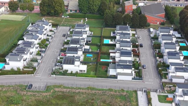 Modern Housing Development: An aerial view showcases a neatly planned housing development featuring contemporary houses with solar panels, swimming pools, and well-maintained gardens.
