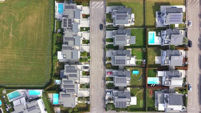 Aerial View of Modern Homes: An overhead perspective showcases a serene suburban neighborhood featuring rows of contemporary houses with solar panels and private swimming pools.
