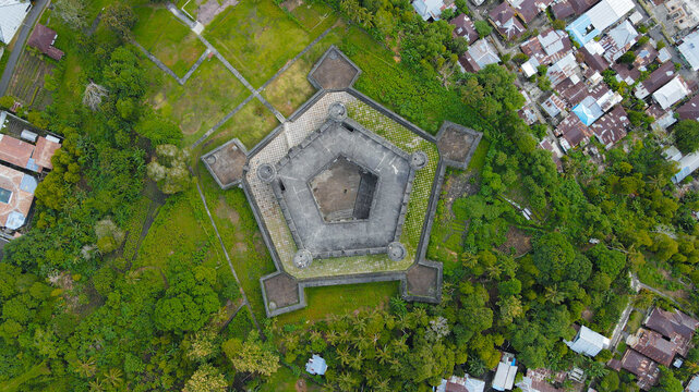 Aerial view of Fort Belgica, a historic pentagonal fortress surrounded by lush greenery and nearby residential buildings in Indonesia.