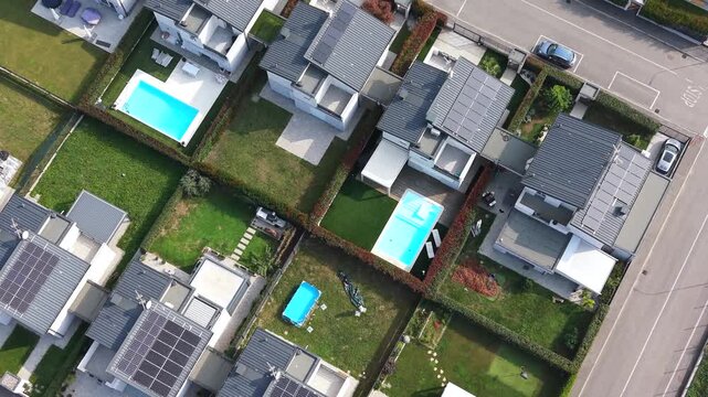 Aerial View of Suburban Homes: An overhead perspective showcases a neat row of modern residential houses with well-maintained gardens and swimming pools, suggesting a tranquil suburban lifestyle.