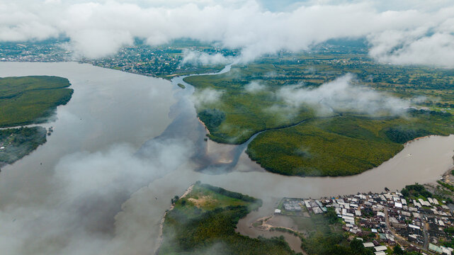 Aerial view of the Kwa Ibo River estuary with lush mangrove forests, winding waterways, and a coastal settlement under a cloudy sky in Kwa Ibo, Akwa Ibom, Nigeria.