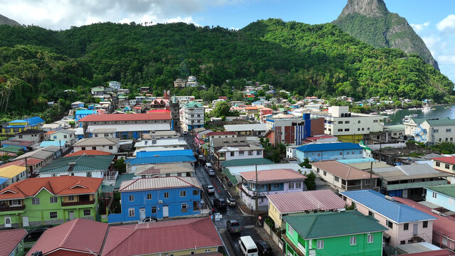 Aerial view of the colorful town of Soufriere nestled between lush green mountains and the Caribbean Sea, featuring vibrant houses and a church in Soufriere, Soufriere, Saint Lucia.