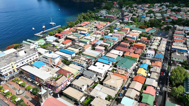 Aerial view of the colorful coastal town of Soufriere with its historic church, dense residential buildings, and boats docked in the harbor in Soufriere, Soufriere, Saint Lucia.