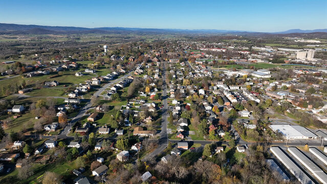 Aerial view of the city of Harrisonburg with residential neighborhoods, local roads, and autumn foliage under a clear blue sky in Harrisonburg, Virginia, United States.