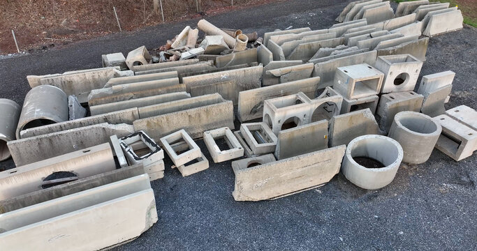 Aerial view of concrete construction materials including pipes, barriers, and blocks arranged on an asphalt surface in Manheim, Pennsylvania, United States.