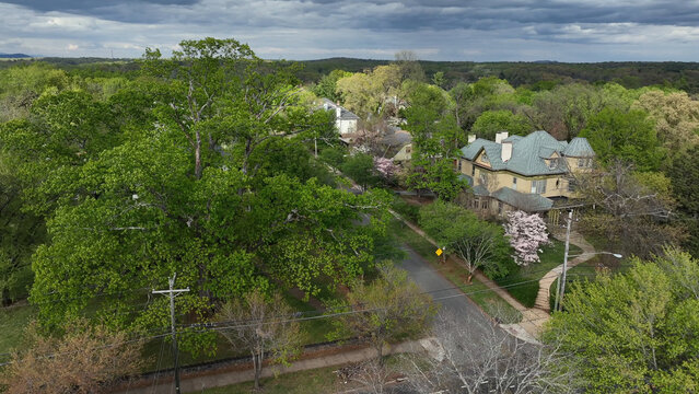 Aerial view of a historic house surrounded by lush green spring trees and a quiet street in a residential neighborhood in Lynchburg, Virginia, United States.