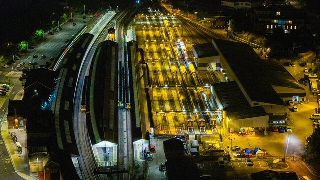 Aerial view of the illuminated Salisbury Railway Station at night with trains parked on the tracks and station platforms visible in Salisbury, England, United Kingdom.
