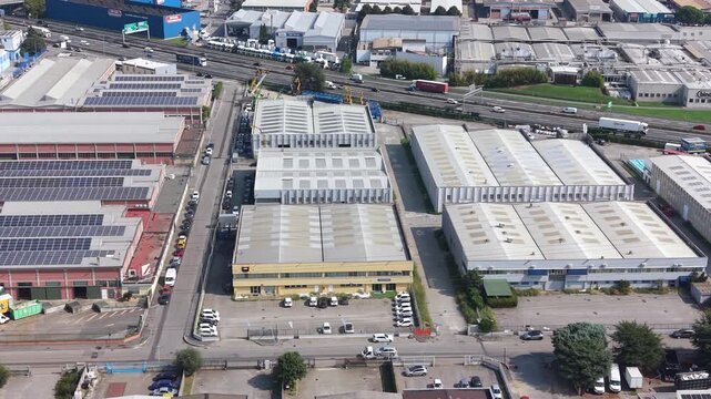 Industrial Zone Aerial View: An expansive aerial perspective reveals a sprawling industrial zone, characterized by rows of warehouses, factories, and a busy highway.