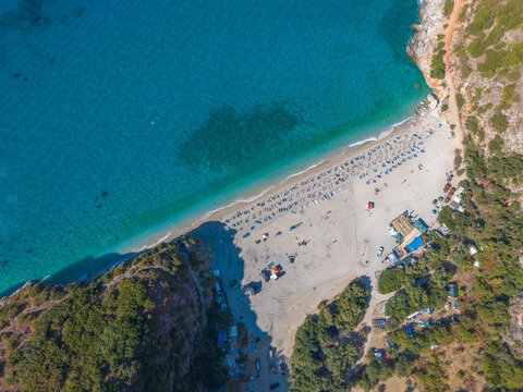 Aerial view of Gjipe Beach with turquoise waters, sandy shore, sun loungers, and surrounding cliffs in Vlore County, Albania.