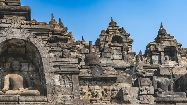 Ancient Hindu architecture. Details. A fragment of the famous temple  Candi Borobudur. Buddha statues in niches, sculptures of mythological creatures, stone carvings. Stupas against a blue sky. Java.

