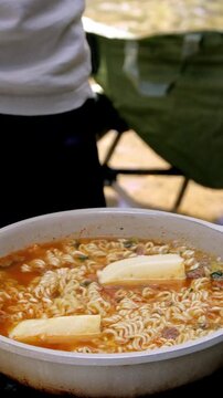 Outdoor cooking during a korean picnic (sopung), adding butter to a simmering pan of instant noodles or ramyeon