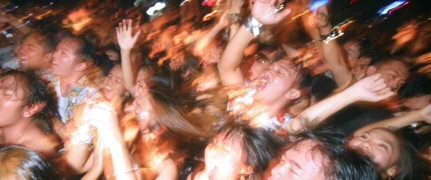 Excited people with hands raised enjoying a lively concert or party