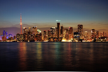 Obraz premium Toronto skyline at dusk with illuminated city lights reflecting on the water, vibrant urban night view. g.