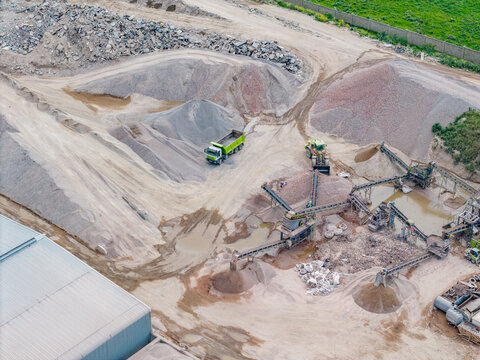 Aerial view of the Philippi quarry featuring a dump truck, industrial conveyor belts, and large piles of gravel in an industrial site in Cape Town, Western Cape, South Africa.