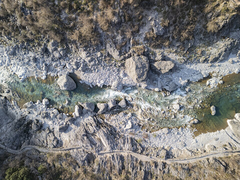 Aerial view of the turquoise waters of the Kiri River flowing through a rugged rocky riverbed with large boulders and a winding path along the bank in Shkoder, Qarku i Shkodres, Albania.