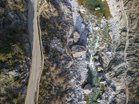 Aerial view of the Kiri River flowing through a rocky landscape with a winding road alongside in Shkoder, Qarku i Shkodres, Albania.