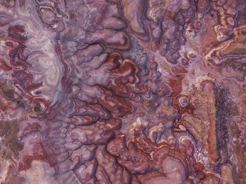 Aerial view of the Bentonite Hills, showcasing unique, vibrant, and layered clay formations with striking red, purple, and grey hues in the desert landscape of Hanksville, Utah, United States.