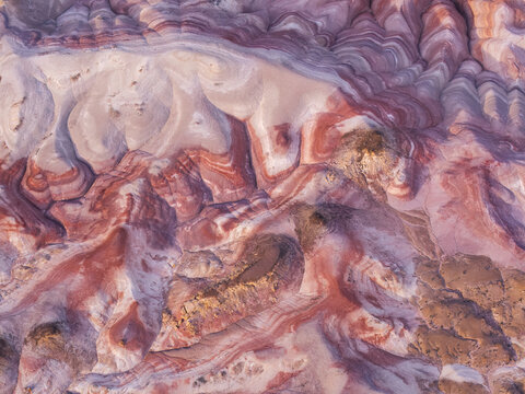 Aerial view of the colorful striped clay mounds of the Bentonite Hills with vibrant red, purple, and white geological layers in the desert landscape of Hanksville, Utah, United States.