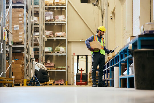 Distribution warehouse worker going through inventory list in storage room.