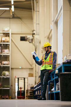 Warehouse worker going through distribution plans in storage compartment.
