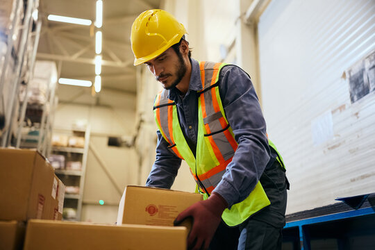 Warehouse worker preparing cardboard boxes for shipment in storage room.