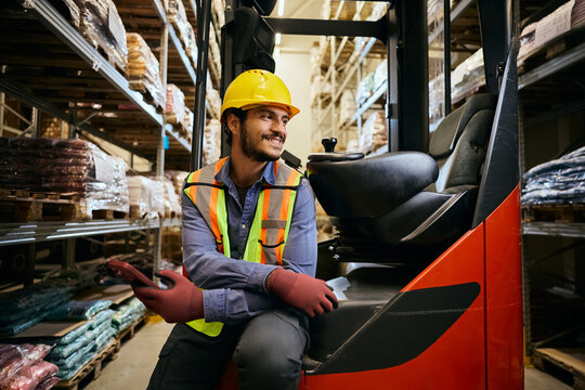 Happy worker by forklift inside of industrial storage facility