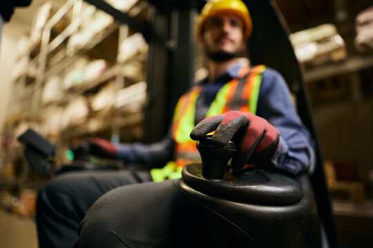 Close up of worker operating forklift while working in warehouse.