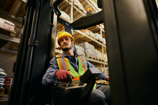 Skilled forklift operator moving merchandise in storage facility.