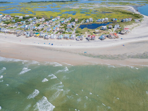 Aerial view of coastal houses lining the sandy beach with a marshland area and the Atlantic Ocean in North Topsail Beach, North Carolina, United States.