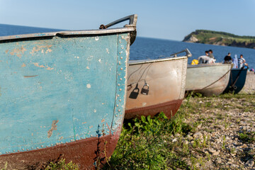 Vintage blue metal boats parked on grassy river shore © Dmitry