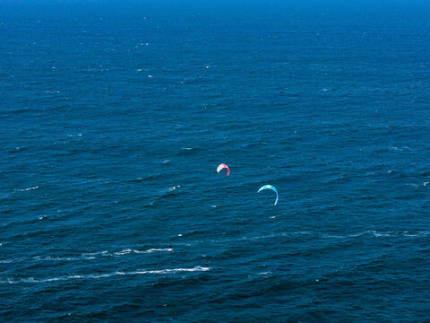 Aerial view of kitesurfers gliding over the deep blue waters of Depok Beach in the Special Region of Yogyakarta, Indonesia.