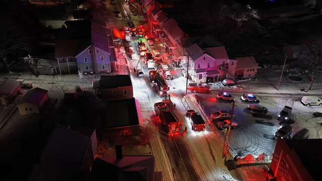Aerial view of emergency vehicles with flashing lights on a snow-covered street at night in a residential area in Ephrata, Pennsylvania, United States.