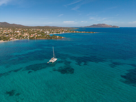 Aerial view of a catamaran anchored in the turquoise waters of the Tyrrhenian Sea off the coast of Pittulongu, Sardinia, Italy.
