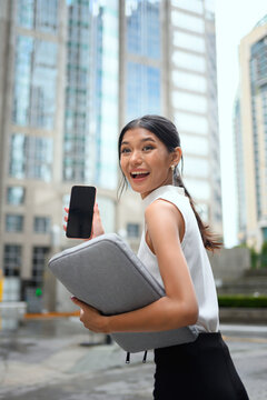Excited Asian Businesswoman Showing Blank Smartphone Screen in City