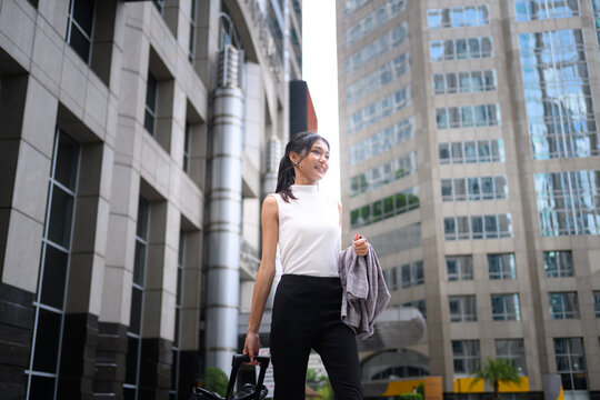 Asian Businesswoman Walking in Urban Financial District with Briefcase
