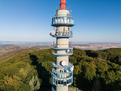 Aerial view of Kekesteto TV Tower in the Matra Mountains, Hungary, with forested slopes and summer panorama under blue sky, featuring telecommunications infrastructure and lookout station