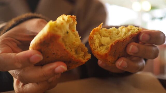 Close up of hands breaking apart savory scone with herbs and vegetables