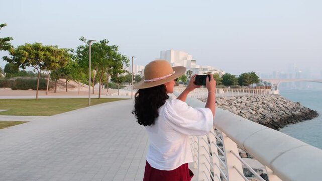 Female traveler exploring Saadiyat Island waterfront with Natural History Museum Abu Dhabi in background during UAE cultural tourism trip